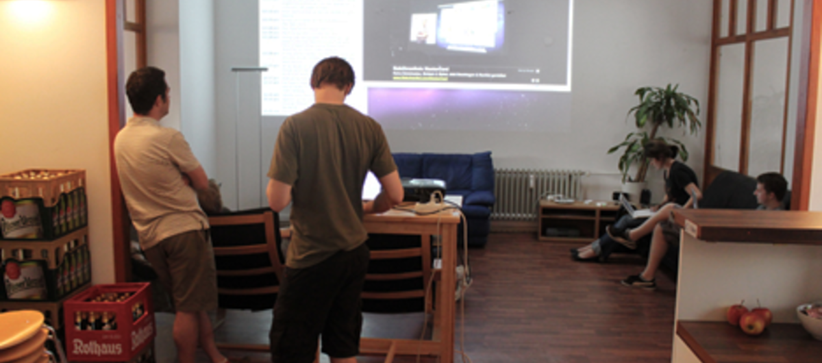 Coworker beim gemeinsamen Schauen eines Konferenz-Live-Streams (im co.up Berlin)